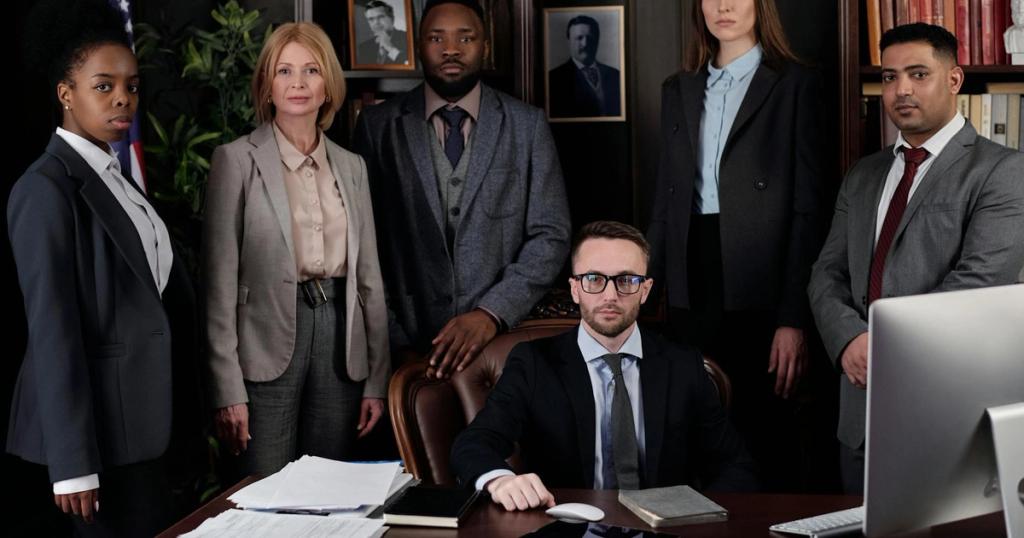 A diverse group of business professionals posing in an office, showcasing teamwork and leadership.