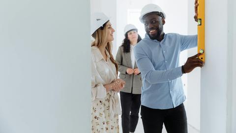 Team of professionals collaborating on a construction project, using leveling tools in a bright indoor space.