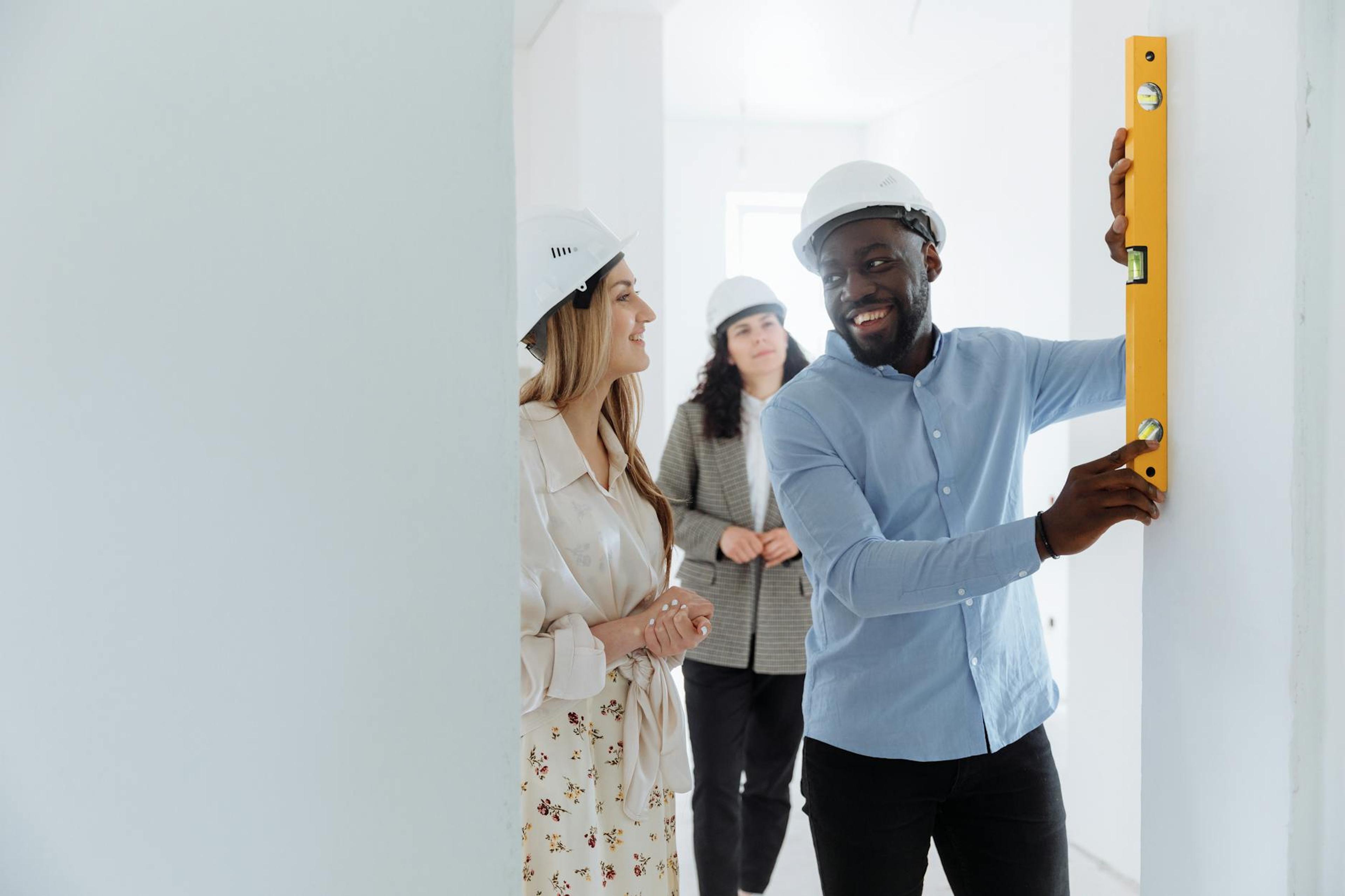 Team of professionals collaborating on a construction project, using leveling tools in a bright indoor space.