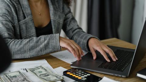 A businesswoman working on finance management with cash and calculator on desk.