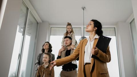 A family with children tours a modern home guided by a real estate agent.