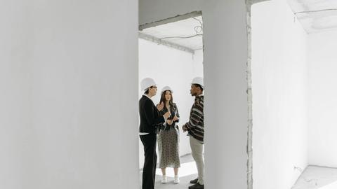 Group discussing potential property purchase inside an unfinished building.