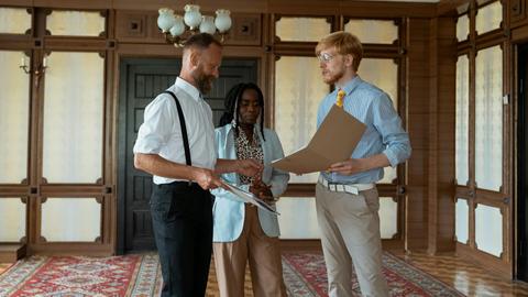 Three business professionals engaged in a discussion in a vintage office setting, showcasing teamwork and collaboration.