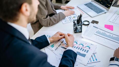 Business team analyzing financial graphs at a meeting table, fostering collaboration in an office environment.