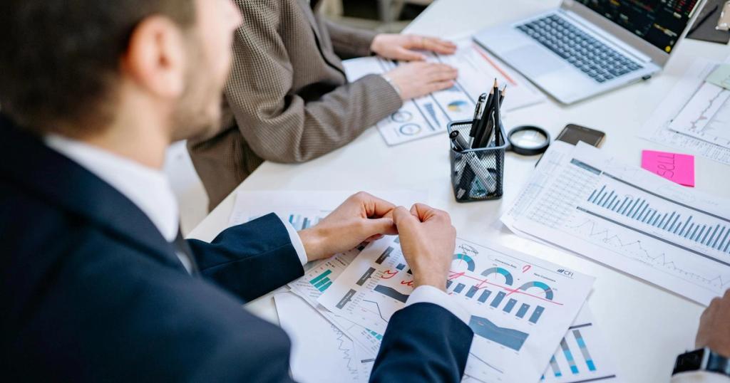 Business team analyzing financial graphs at a meeting table, fostering collaboration in an office environment.