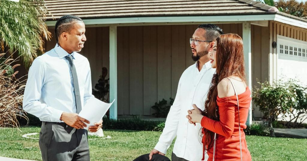 A real estate agent discusses property details with a couple outside a suburban home.