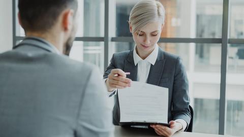 Woman in suit shows document to man