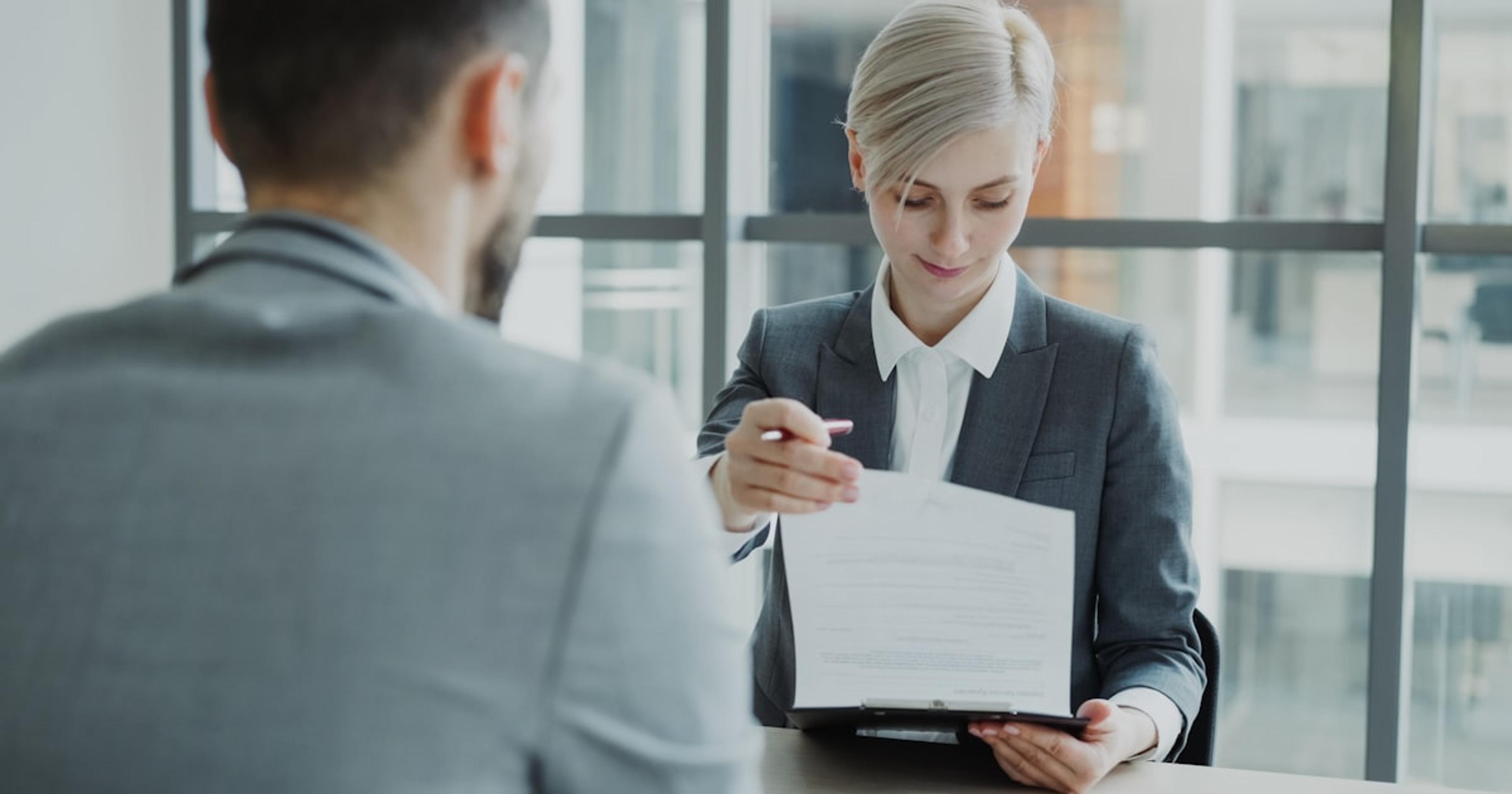 Woman in suit shows document to man
