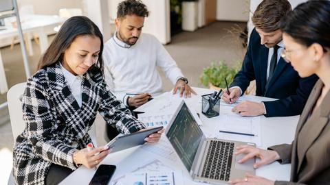 Business team engaged in planning and analysis with laptops and papers at a modern office.