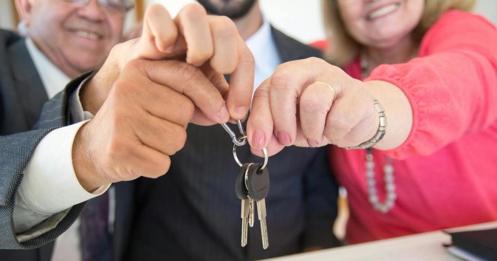 Business colleagues celebrating a successful deal with a handshake and keys exchange.