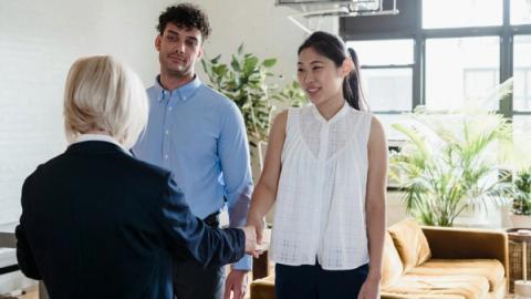 A young couple meeting with a real estate agent in a modern apartment setting.