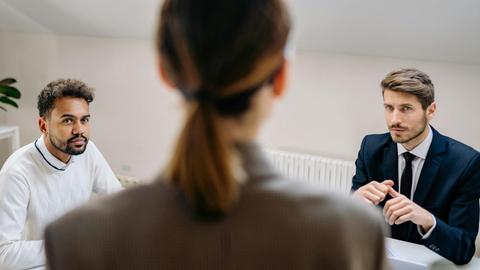 A professional business meeting involving three adults in a modern office setting.