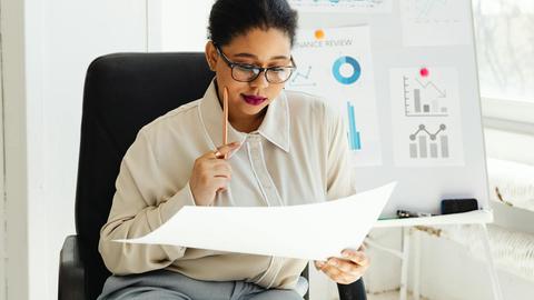 Businesswoman in glasses analyzing financial documents at her office desk.