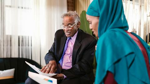 Two professionals in business attire discussing documents in an office setting.