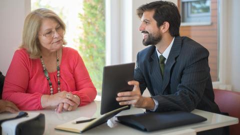 Elderly woman consulting with a realtor about a property deal in a cozy indoor setting.