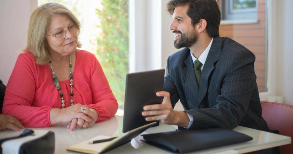Elderly woman consulting with a realtor about a property deal in a cozy indoor setting.
