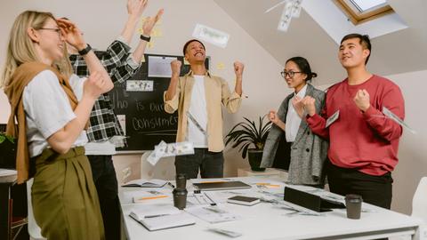 Diverse team excitedly celebrating success in a modern office setting.