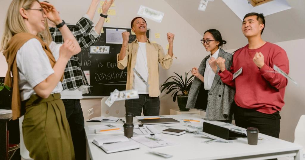 Diverse team excitedly celebrating success in a modern office setting.