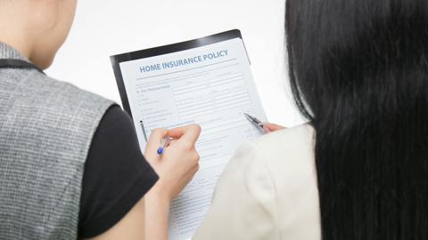 Two women examining home insurance policy form, focused on details.