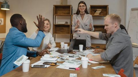 A multicultural team enjoying success during a collaborative business meeting in a modern office.