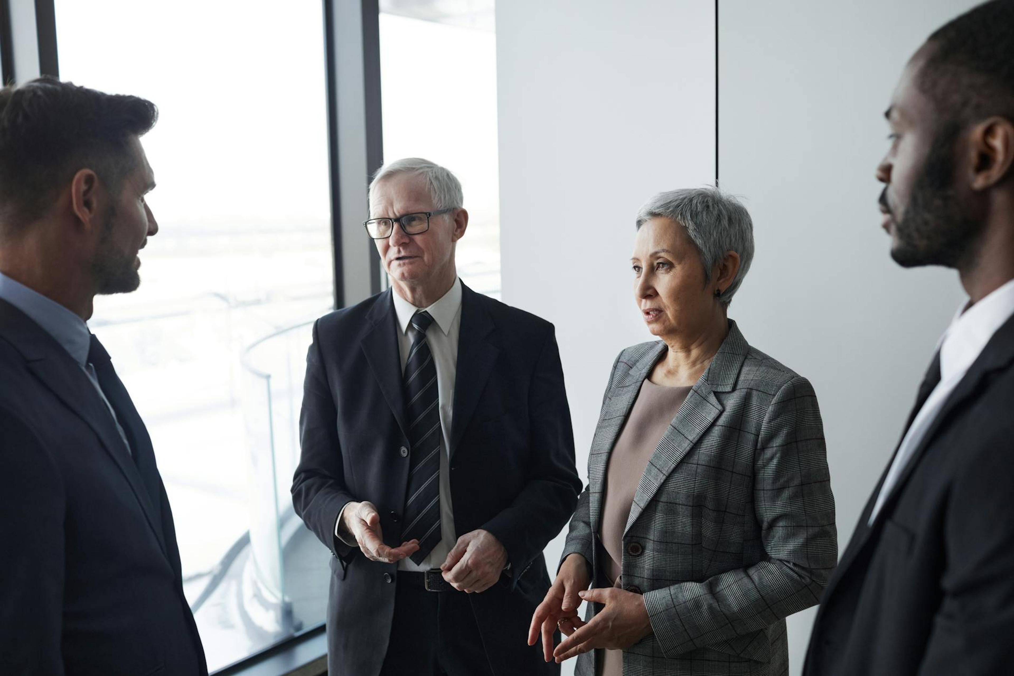 Group of business professionals in a formal meeting setting discussing strategy indoors.