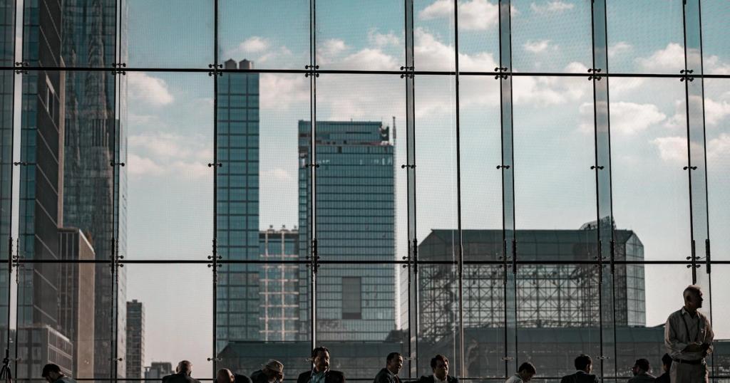 Business professionals at the Javits Center, New York City featuring urban skyline through glass facade.