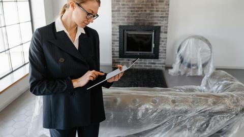A real estate agent in a suit uses a digital tablet to review documents in a modern living room.