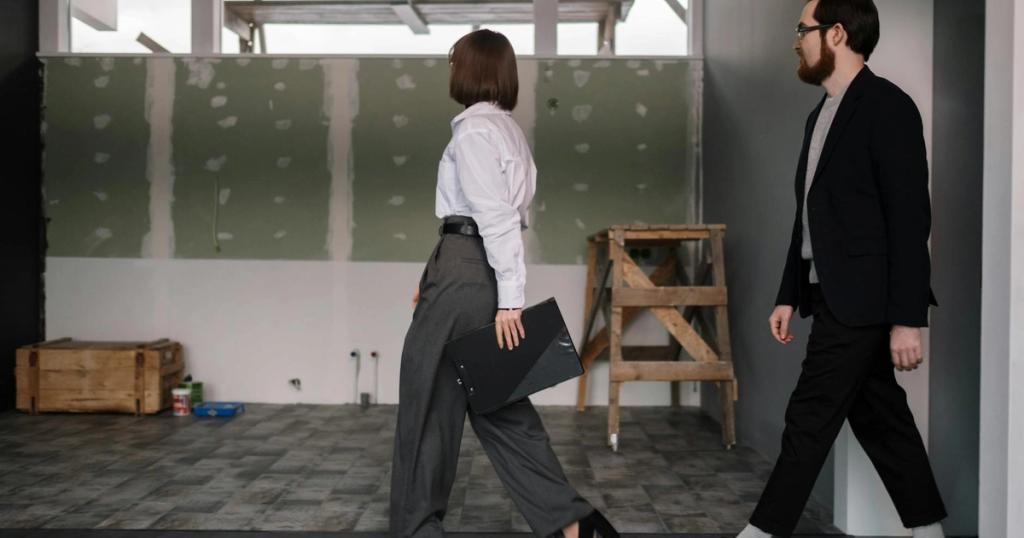 Businessman and businesswoman reviewing office construction progress indoors.