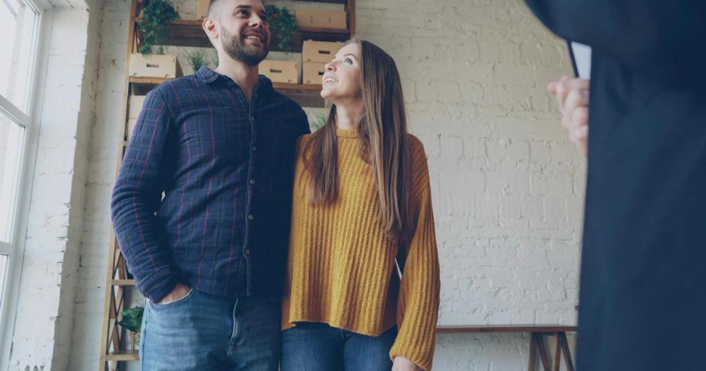 Happy young couple consulting with a real estate agent in a stylish modern home.