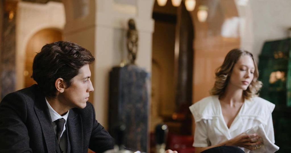 A man and woman engage in conversation at a classic, elegant hotel bar.