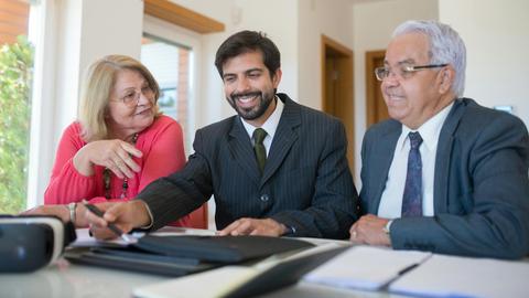 Professional realtor discussing real estate deal with senior couple in bright office setting.