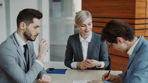 Business people signing a contract at a table.