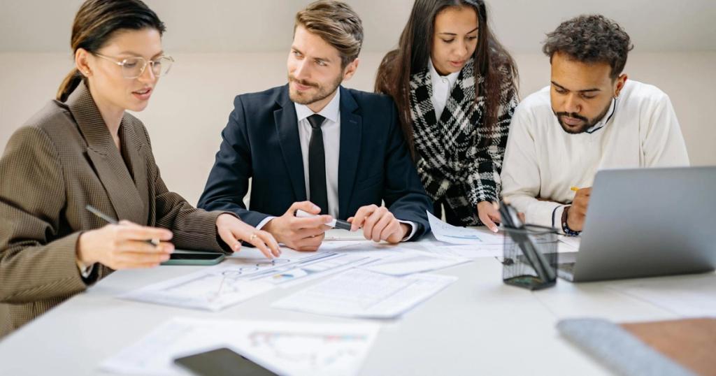 Diverse team discussing a business plan at an office desk with laptops and documents.