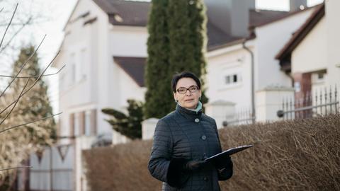 Adult woman in eyeglasses standing outside holding a clipboard, ideal for business or lifestyle themes.