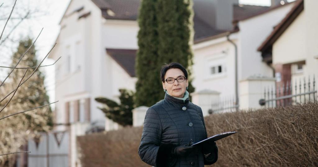 Adult woman in eyeglasses standing outside holding a clipboard, ideal for business or lifestyle themes.