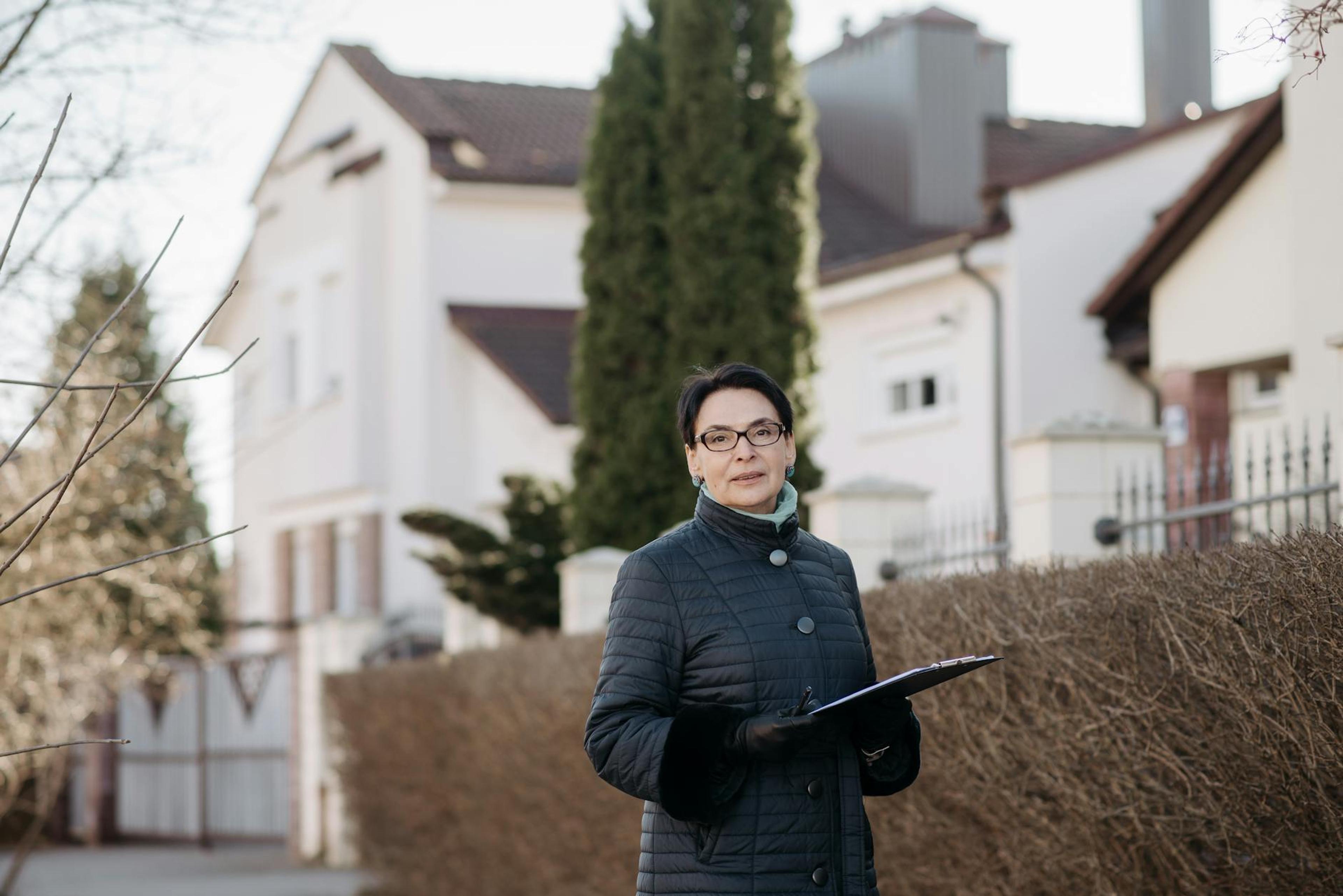 Adult woman in eyeglasses standing outside holding a clipboard, ideal for business or lifestyle themes.
