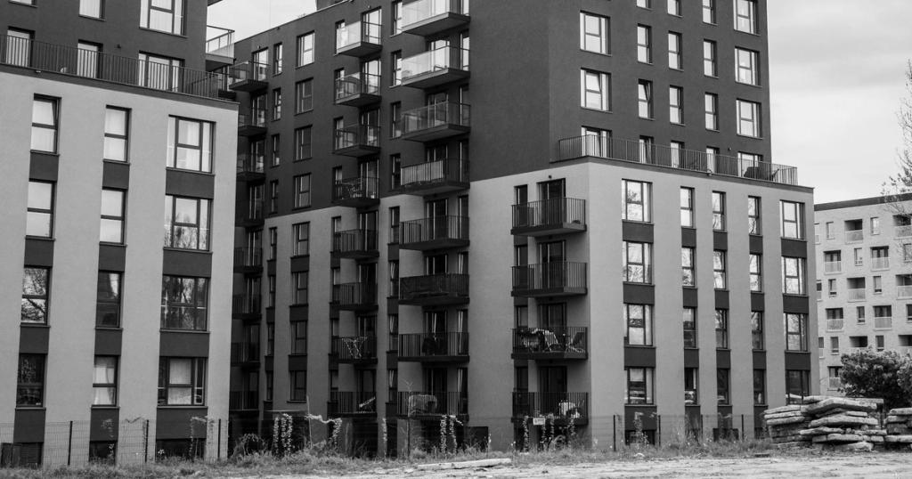 Stylish urban apartment buildings with balconies in grayscale tones, focusing on modern architecture.