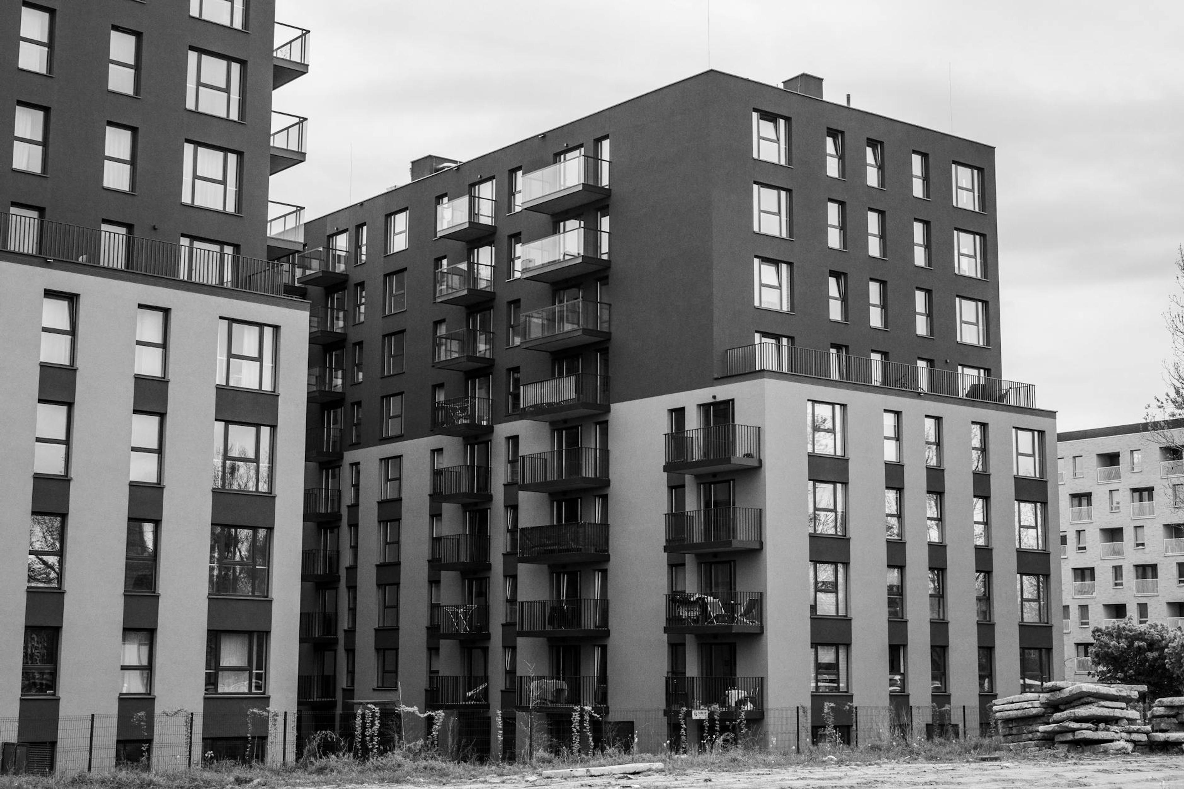 Stylish urban apartment buildings with balconies in grayscale tones, focusing on modern architecture.