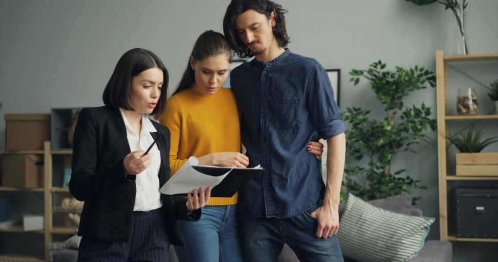 A couple reviewing documents with a real estate agent indoors.