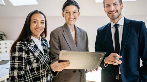 A diverse group of professionals smiling confidently in a modern office environment.