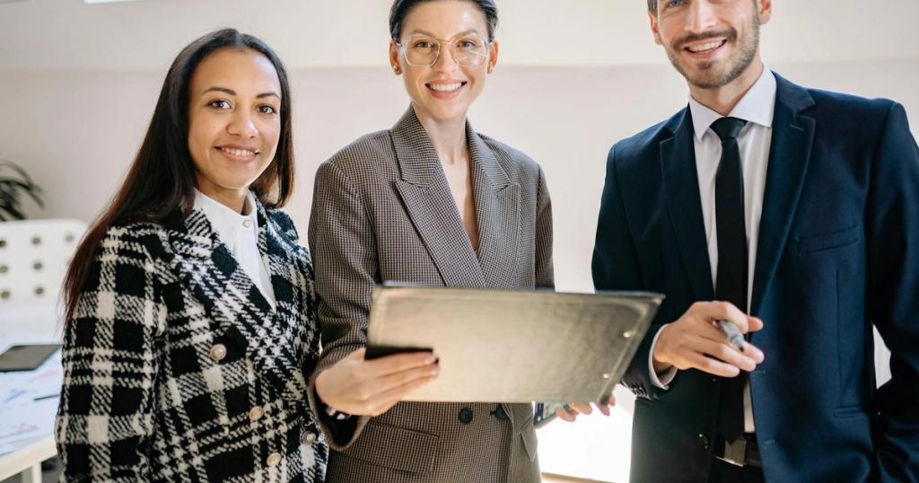 A diverse group of professionals smiling confidently in a modern office environment.