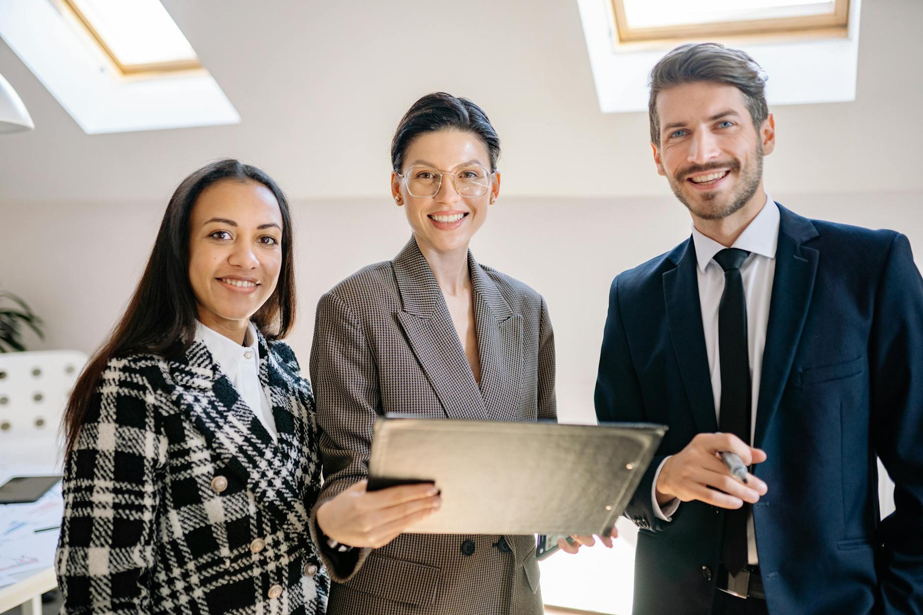 A diverse group of professionals smiling confidently in a modern office environment.
