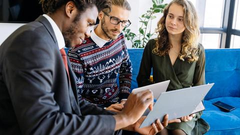 A diverse group of young professionals engaged in a business meeting inside a modern office.