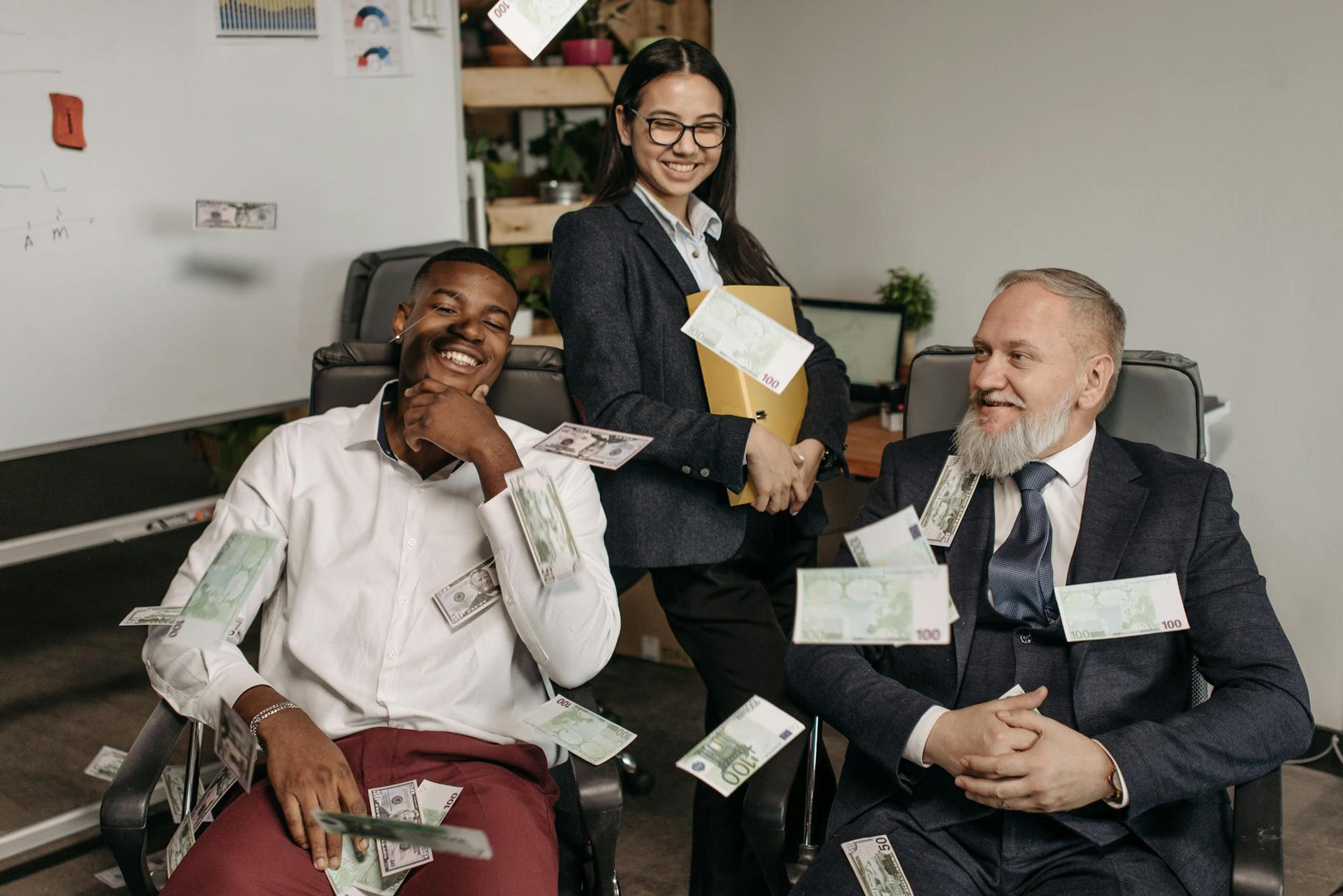 Office scene of diverse business professionals with money scattered, creating a playful environment.