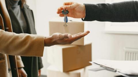 A new homeowner receives keys inside their new home, symbolizing a fresh start.