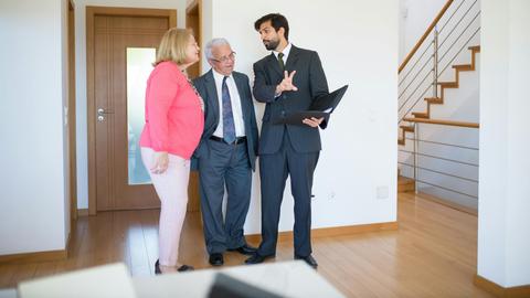 Realtor showing property to senior couple inside a modern home in Portugal.