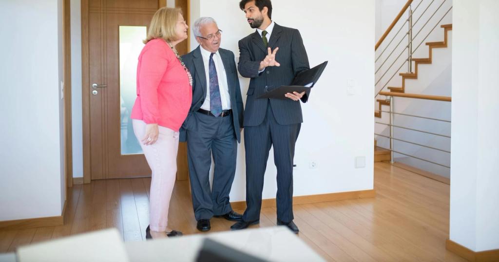 Realtor showing property to senior couple inside a modern home in Portugal.