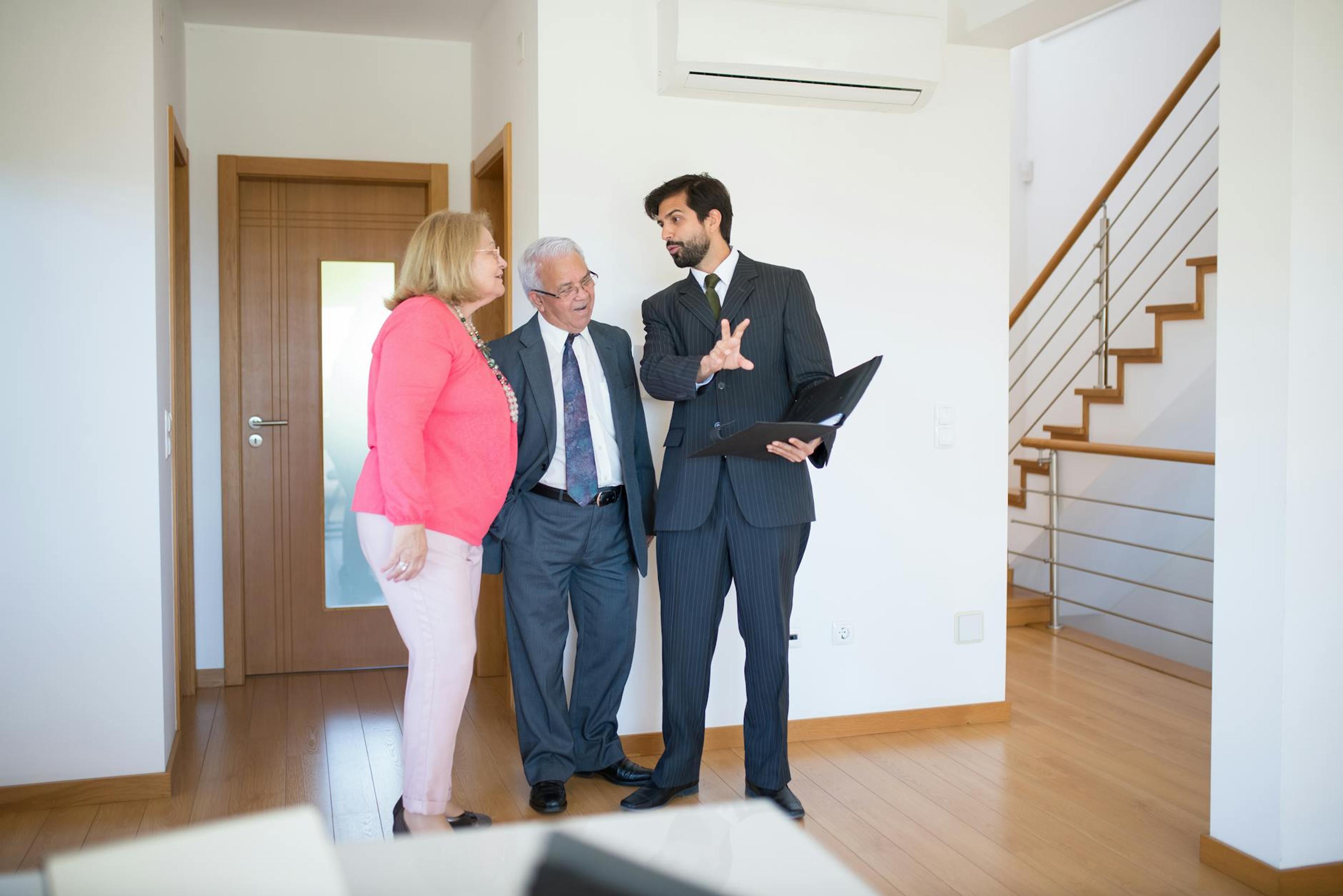 Realtor showing property to senior couple inside a modern home in Portugal.