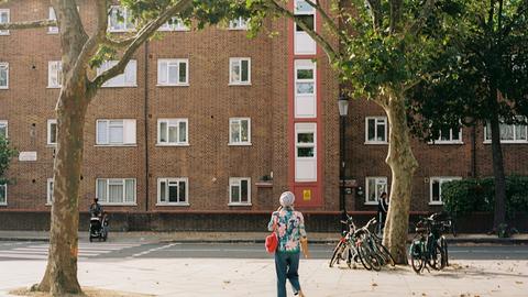 a woman walking down a street next to a tall brick building