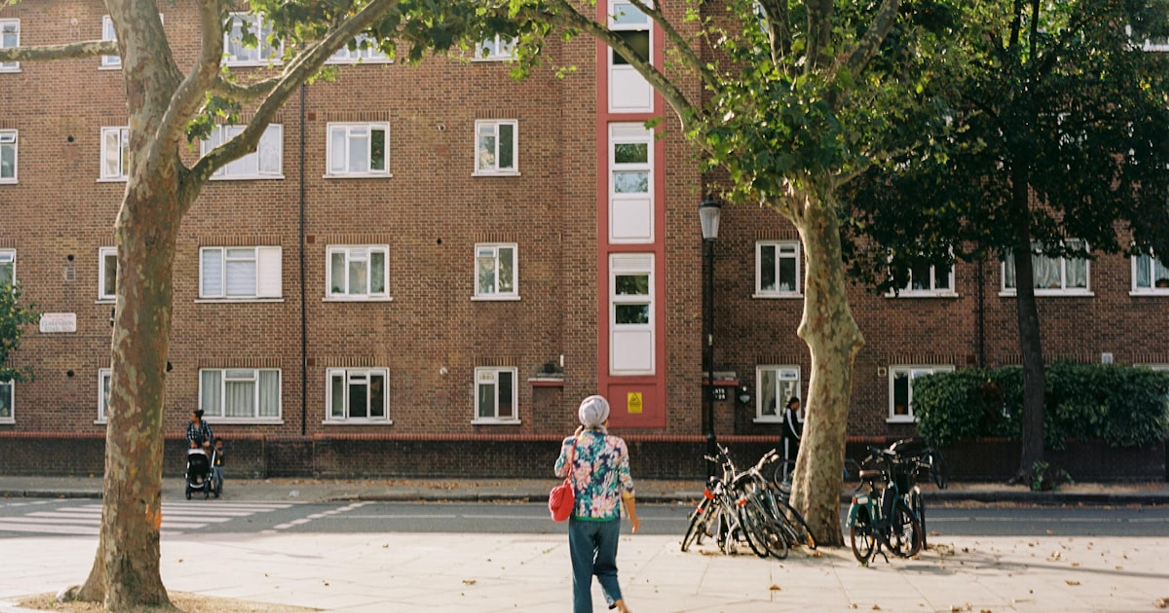 a woman walking down a street next to a tall brick building